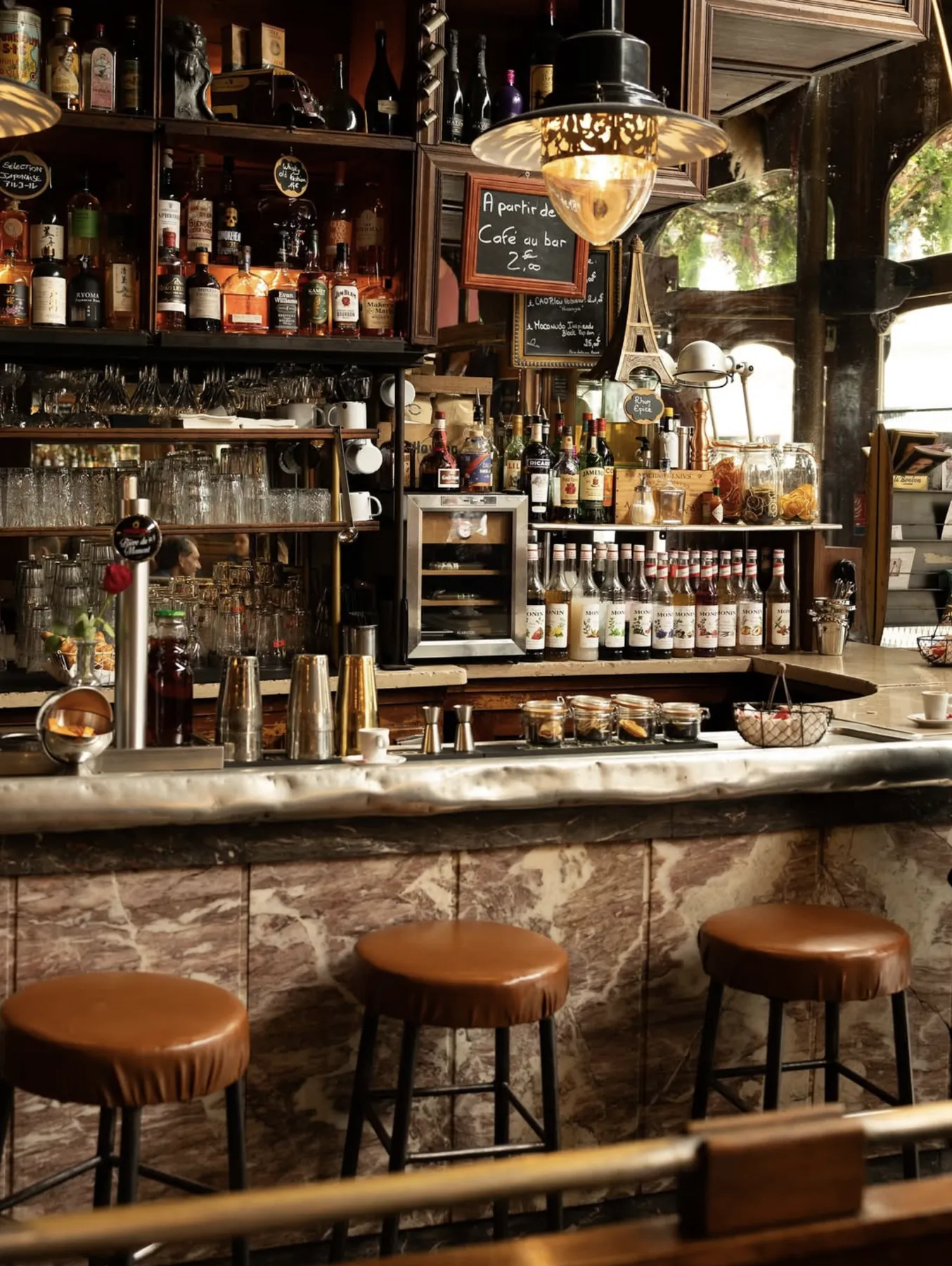 Le comptoir du Café Charbon et ses bouteilles sous les lampes d'époque